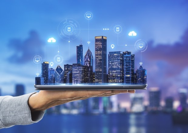 Smart city technologies concept with digital tablet and night megapolis city skyscrapers with digital cloud icons on human hand at blurry skyline background