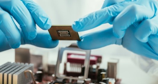partial view of engineer holding microchip near computer motherboard