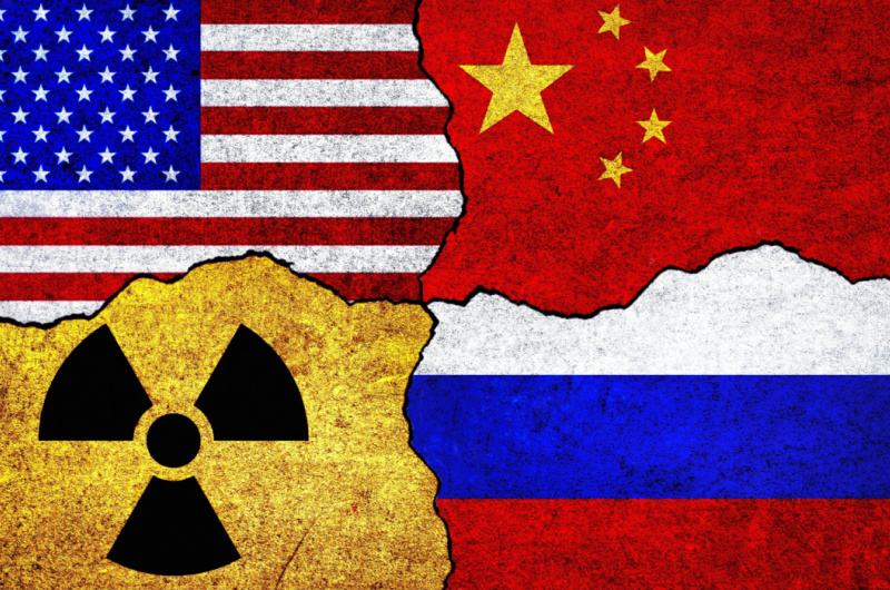 Flags of USA, Russia, China and radiation symbol on a wall.