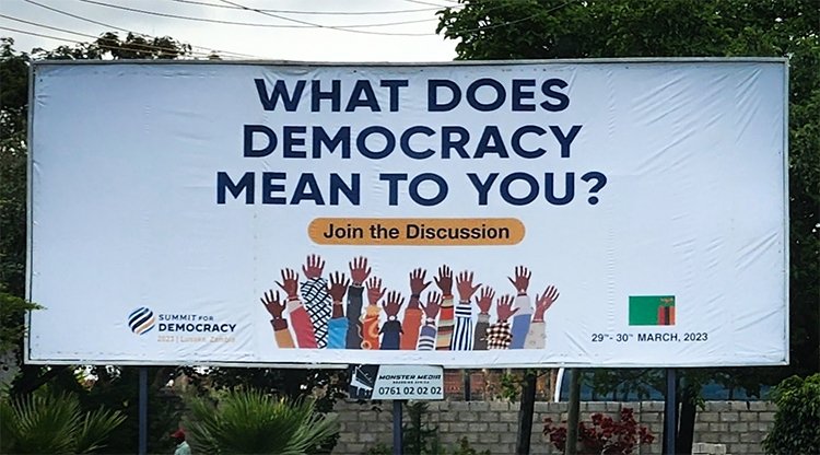 Billboard displaying "What does democracy mean to you"? for the 2023 Summit for Democracy