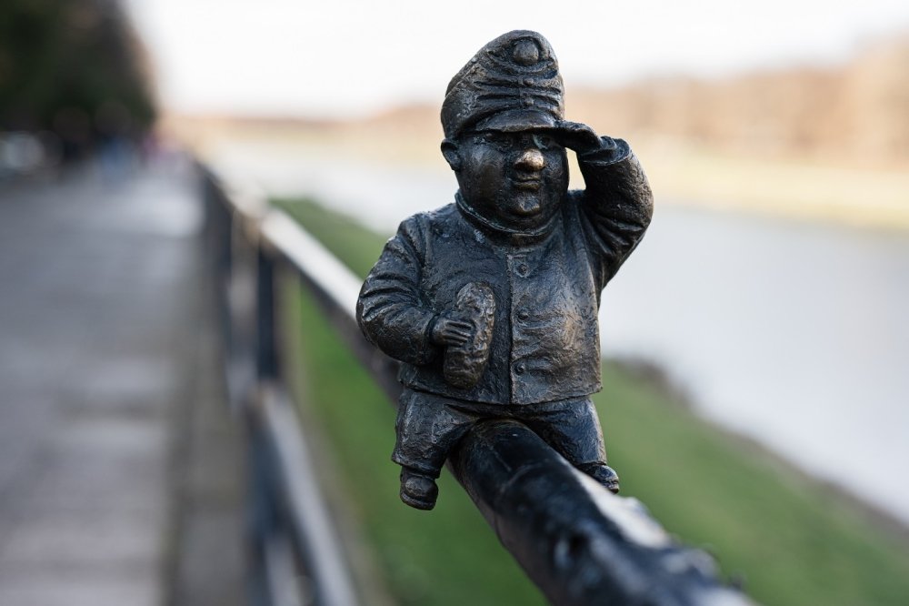 Small metal statue sitting on a fence 