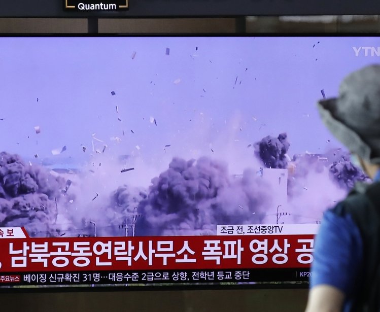 A man watching a TV screen showing a news program with a video of the demolition of the inter-Korean liaison office building in Kaesong, North Korea.