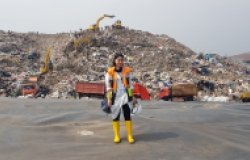 Woman standing in front of multi-colored landfill site
