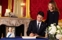 Justin Trudeau signs a book of condolence with his wife Sophie Grégoire-Trudeau at Lancaster House after the death of Queen Elizabeth II.