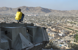 KABUL, AFGHANISTAN 2012: Boy sitting on Destroyed Tank on the hills over Kabul City in Afghanistan