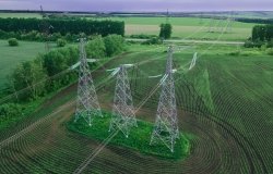 High voltage electric power tower in a green agricultural landscape at beautiful sunset