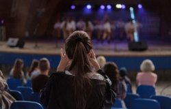 Girl taking a photo of dancers on the stage. 