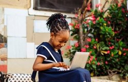 Young African girl working on a laptop computer. 